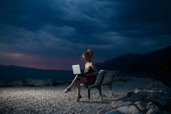 Femme avec ordinateur portable sur la plage du soir — Photo