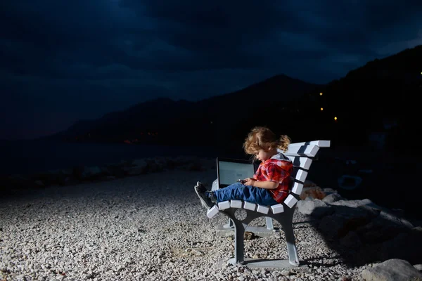 Söt pojke med laptop på stranden — Stockfoto