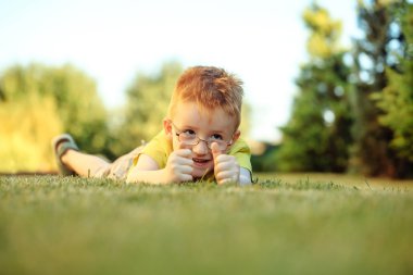 Çimenlerin üzerinde bardaklarda Kızıl saçlı erkek mutlu bebek