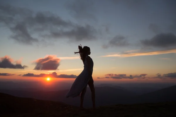 Mulher ao pôr-do-sol ou nascer do sol nas montanhas — Fotografia de Stock