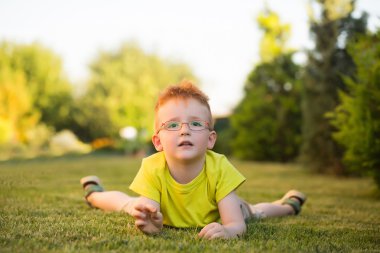 Çimenlerin üzerinde bardaklarda Kızıl saçlı erkek mutlu bebek