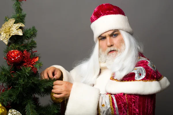 Серьёзный Санта украшает ёлку — стоковое фото
