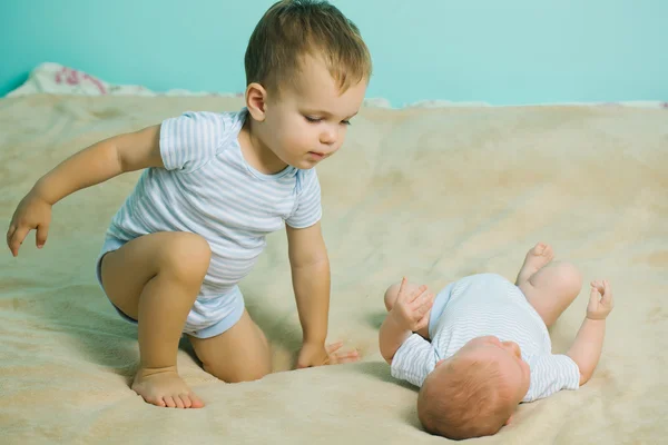 Pequeño niño juega con recién nacido — Foto de Stock