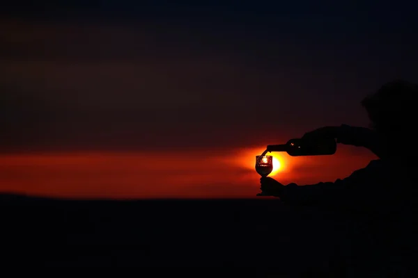 Hands pouring wine on sunset — Stock Photo, Image