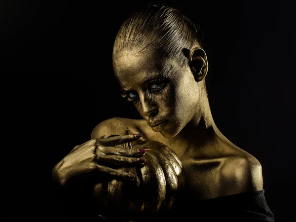 Gouden vrouw met Halloween pompoen — Stockfoto