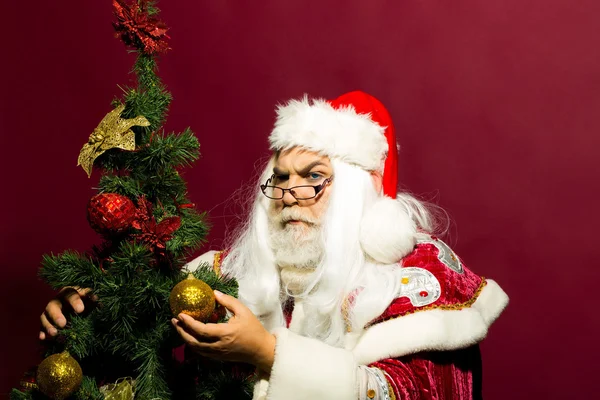 Allvarliga santa dekorerar granen — Stockfoto