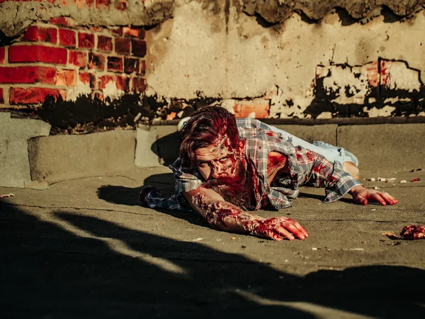 Zombie man crawls on asphalt