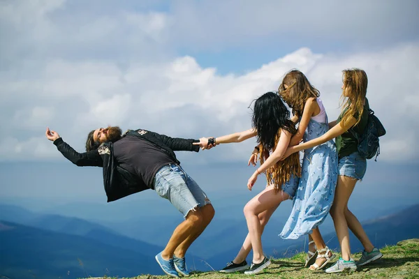 Drie mooie meisjes trekken man — Stockfoto