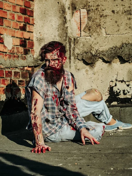 Zombi adam asfalt üzerinde oturur