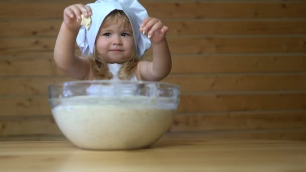Cute baby in cook cap playing with dough — Stock video