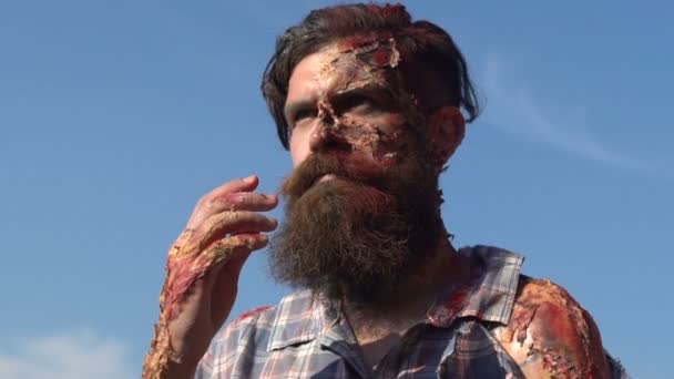 Bearded man touches the face with scars on a sky background — Stock video