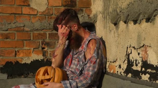 Бородатый человек со шрамами держа тыкву и удалить с лица Хэллоуин макияж — стоковое видео