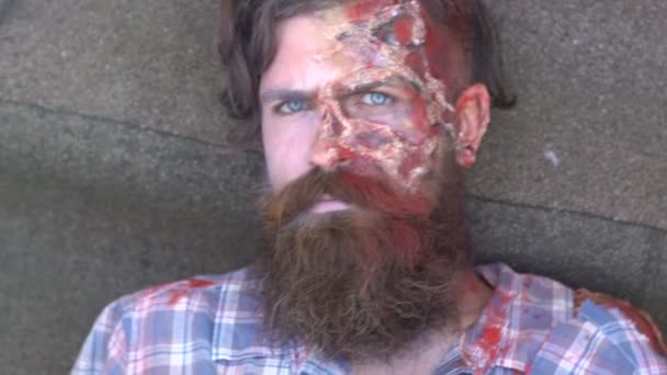 Man with scars dying on the street, bearded zombie closes blue eyes after Halloween — Stock Video