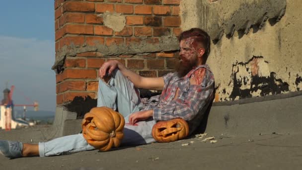 Young attractive man with monster zombie make up and pumpkins — Stock Video