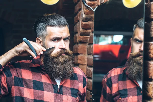 Человек с бритвой возле зеркала — стоковое фото