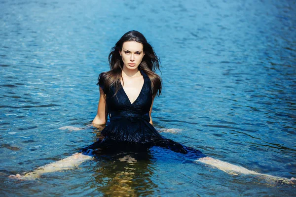 Sexy chica joven se sienta en el agua — Foto de Stock