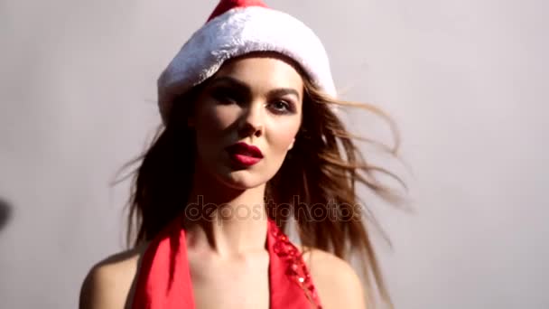 Blonde klap ronde door een fan in Santas hoed draaien haar hoofd — Stockvideo