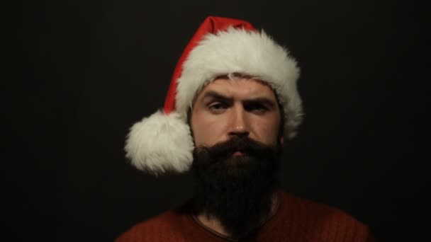 Emotionele bebaarde jongeman in de hoed van de Kerstman verplaatst zijn wenkbrauwen — Stockvideo