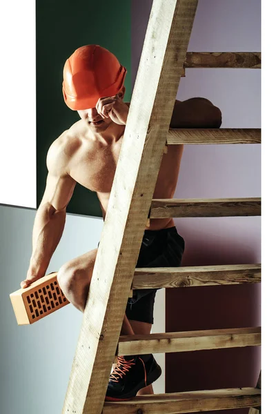 Sexy gespierde man bouwer op de ladder — Stockfoto