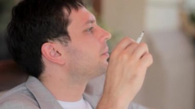 Genç adam terasta sigara içiyor ve mesafe içine görünüyor