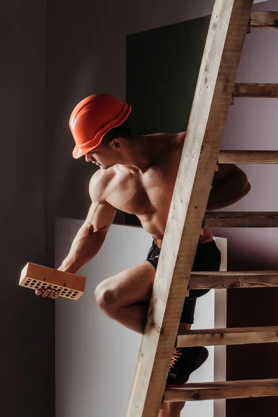 Sexy gespierde man bouwer op de ladder — Stockfoto