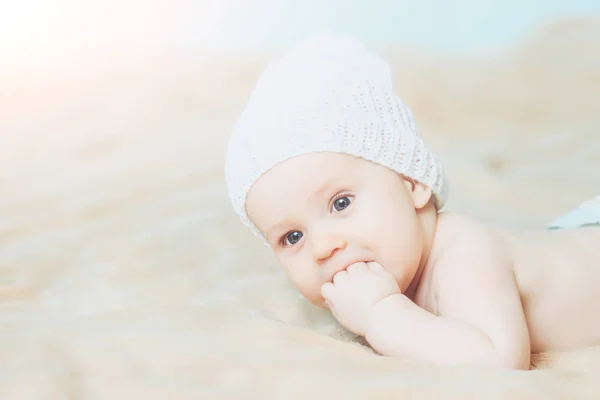 Malý chlapeček v bílém klobouku s prsty v ústech — Stock fotografie