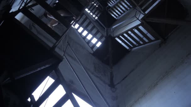 Barfota flicka klättrar på stegen i en industribyggnad — Stockvideo
