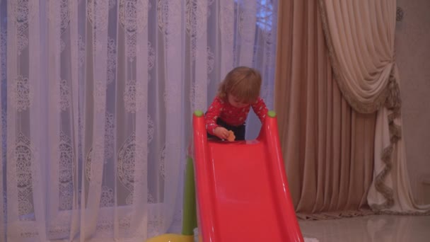 Baby is playing on a children's slide nearby the Christmas tree — Stock Video