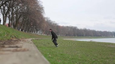 Genç çocuk yapmak parkour egzersiz bir nehir dolgu