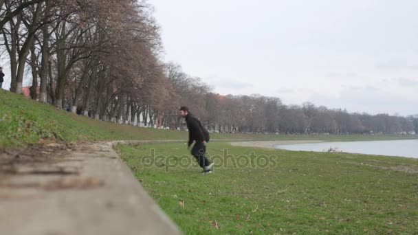 Mladý chlapec dělat parkour cvičení na nábřeží řeky — Stock video