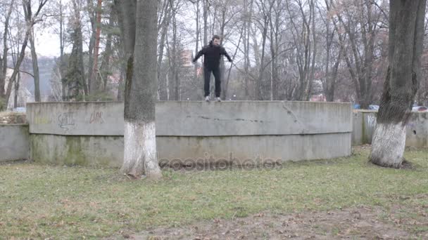 Ung idrottsman utbildning parkour på en stenmur i parken — Stockvideo