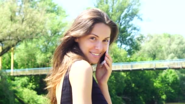 Ralenti : Jolie femme brune avec un beau sourire parlant au téléphone et souriant — Video