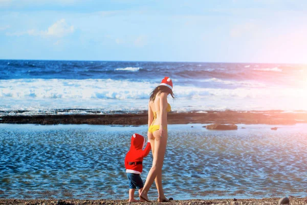 Santa jongen en vrouw aan het strand — Stockfoto