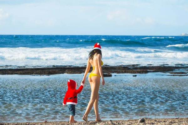 Santa boy and woman at beach — Stock Photo, Image