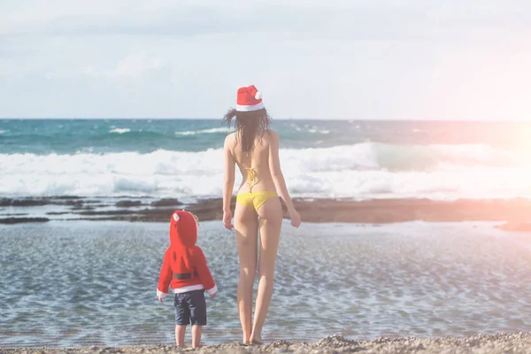 Santa jongen en vrouw aan het strand — Stockfoto