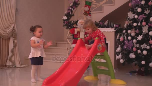 Bébé garçon et fille mignonne avoir beaucoup de plaisir tout en descendant la glissière dans un salon de Noël — Video