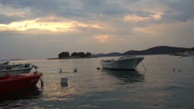 Balıkçı köyü yakınlarında deniz sahilde günbatımı. Balıkçı tekneleri, Adriyatik Denizi küçük limanında demirlemiş. Sakin bir koyda Hırvatistan'daki teknelerden pitoresk sahne
