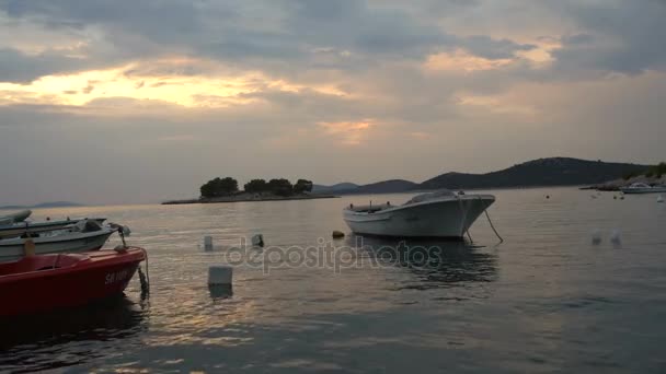 漁村の近く海のビーチに沈む夕日。アドリア海の小さな港に停泊漁船します。クロアチアでの静かな湾の船の絵になる風景 — ストック動画