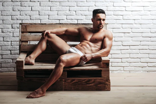 Schöner muskulöser Mann auf Holzbank — Stockfoto