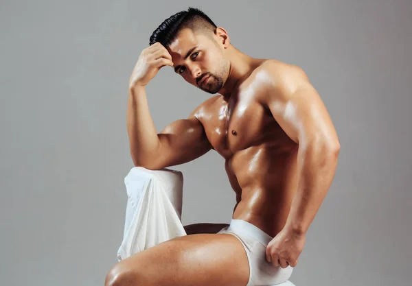 Guapo culturista se sienta en la silla — Foto de Stock