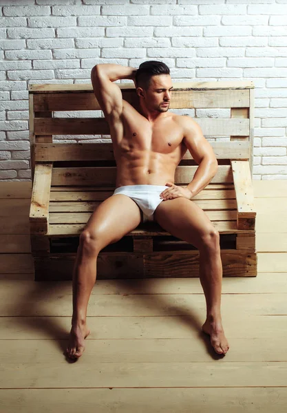 Hombre musculoso guapo en banco de madera — Foto de Stock