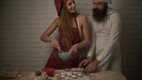 Dívka šéfkuchař hodí vejce smažená vejce a její manžel pomáhá, aby potraviny s moukou a laská jeho přítelkyně — Stock video