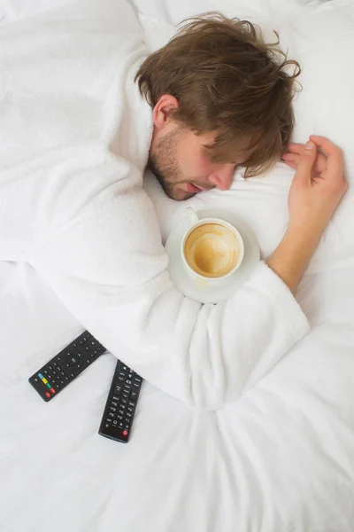 stock image bearded man on bed with remote