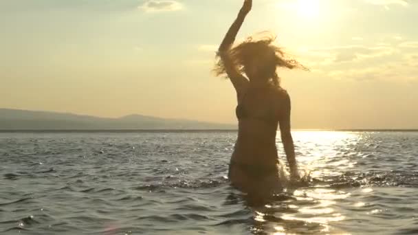 Vida marina, olas y salpicaduras de agua de una hermosa chica en el fondo del atardecer. Movimiento lento — Vídeos de Stock