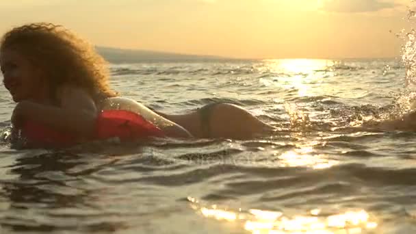 Sexig tjej simmar i havet vid solnedgången. Sexuell kvinna i förföriska baddräkt badar i havet på sommaren. Turism-konceptet — Stockvideo
