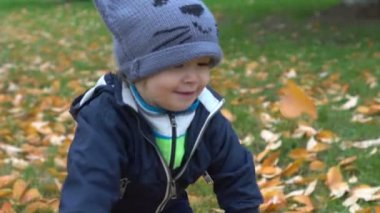Ağır çekim: iskambil ile kedi şapkalı çocuk bırakır bahçede sonbaharda. Sonbahar yürüyüş ve çocuk eğlence açık havada oyun