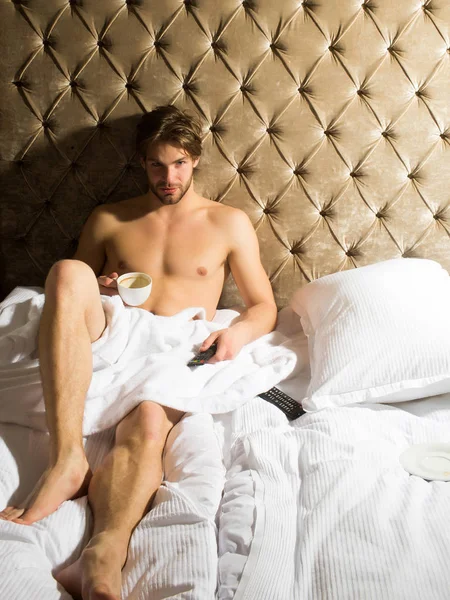 bearded man on bed with coffee