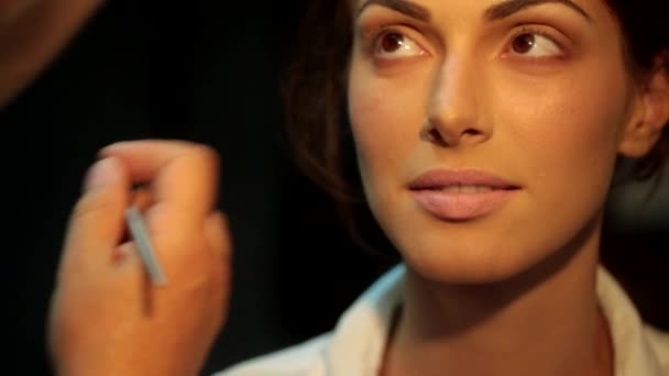 Καλλιτέχνης μακιγιάζ κάνει τα χείλη και το περίγραμμα των ματιών για το μοντέλο στο στούντιο — Αρχείο Βίντεο