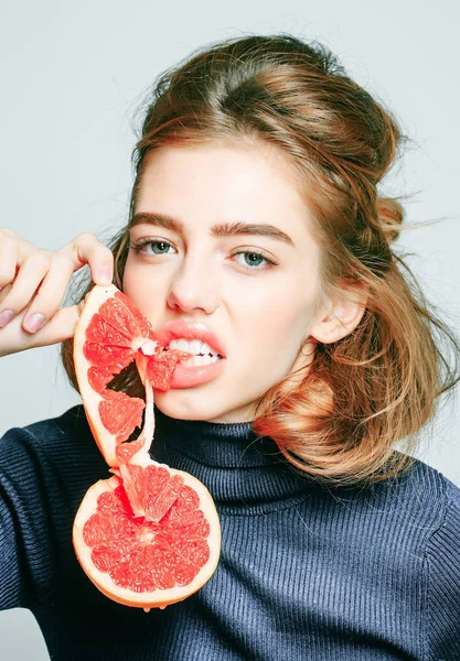 Hezká dívka kousnutí grapefruitové řezy — Stock fotografie
