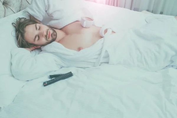 bearded man on bed with remote